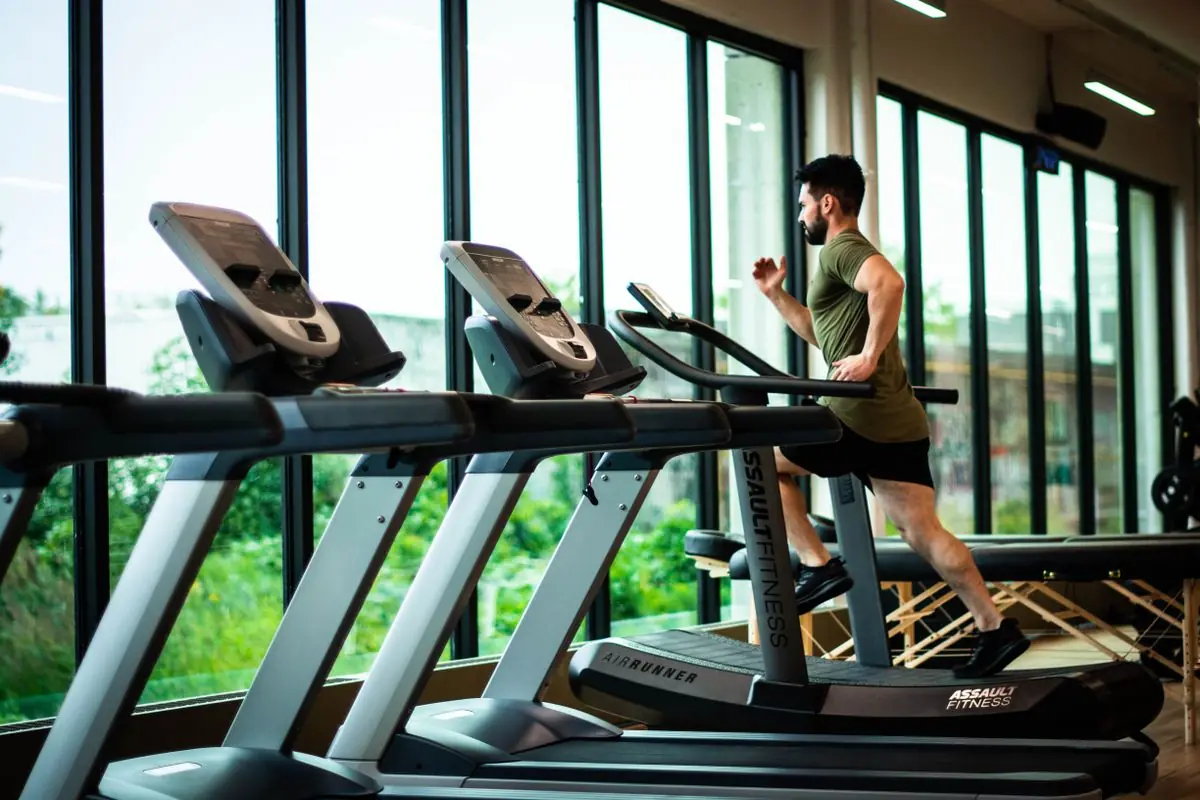 Person training on a treadmill in a bright, glass-walled gym