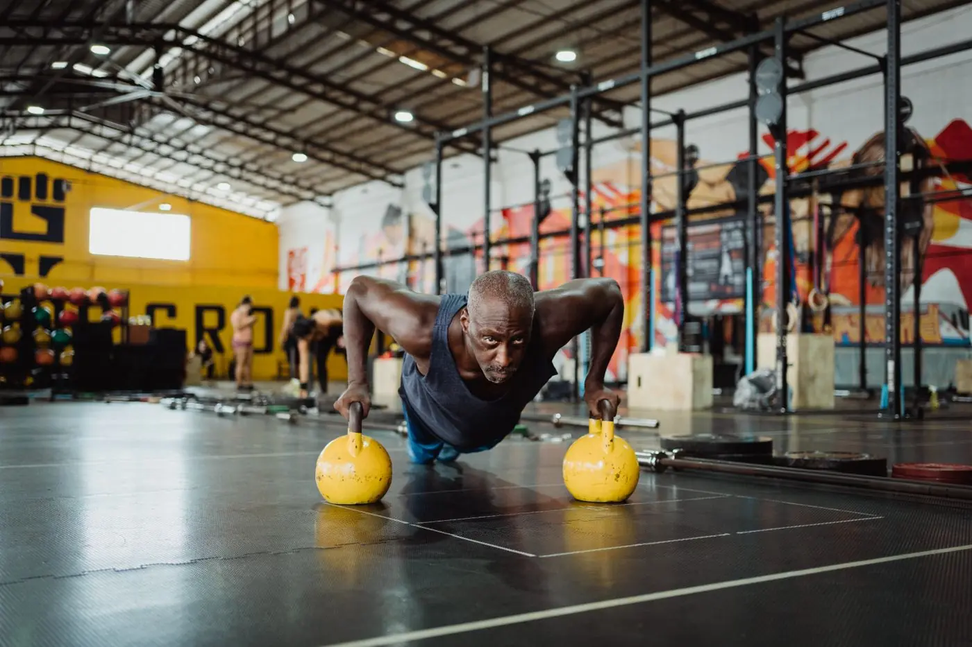 Athlete training with kettlebells in a busy neighbourhood gym