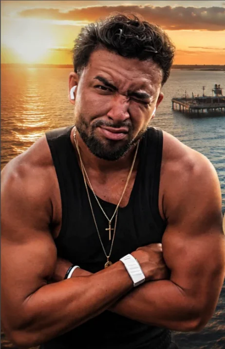 Jordan with his arms crossed in front of a sunset over the water